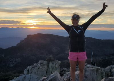 A Woman Standing On A Rock With Her Arms Up