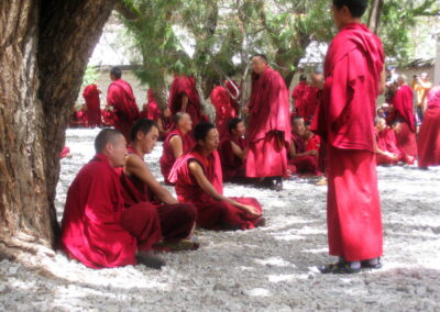 A Group Of People In Red Robes With Sera Monastery In The Background