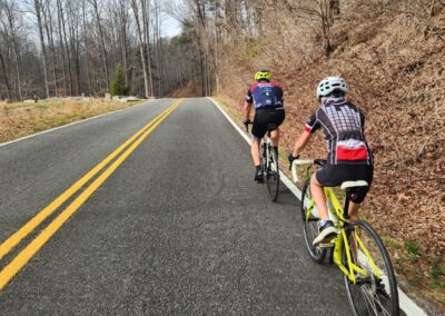 Two People Riding Bicycles On A Road