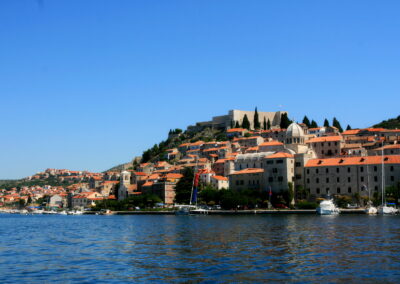 A City On A Hill With A Hill And A Boat On The Water