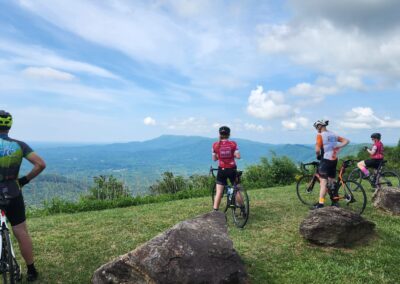 Two People On Bicycles On A Hill Overlooking A Valley