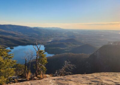 A View Of A Lake And Mountains From A Cliff